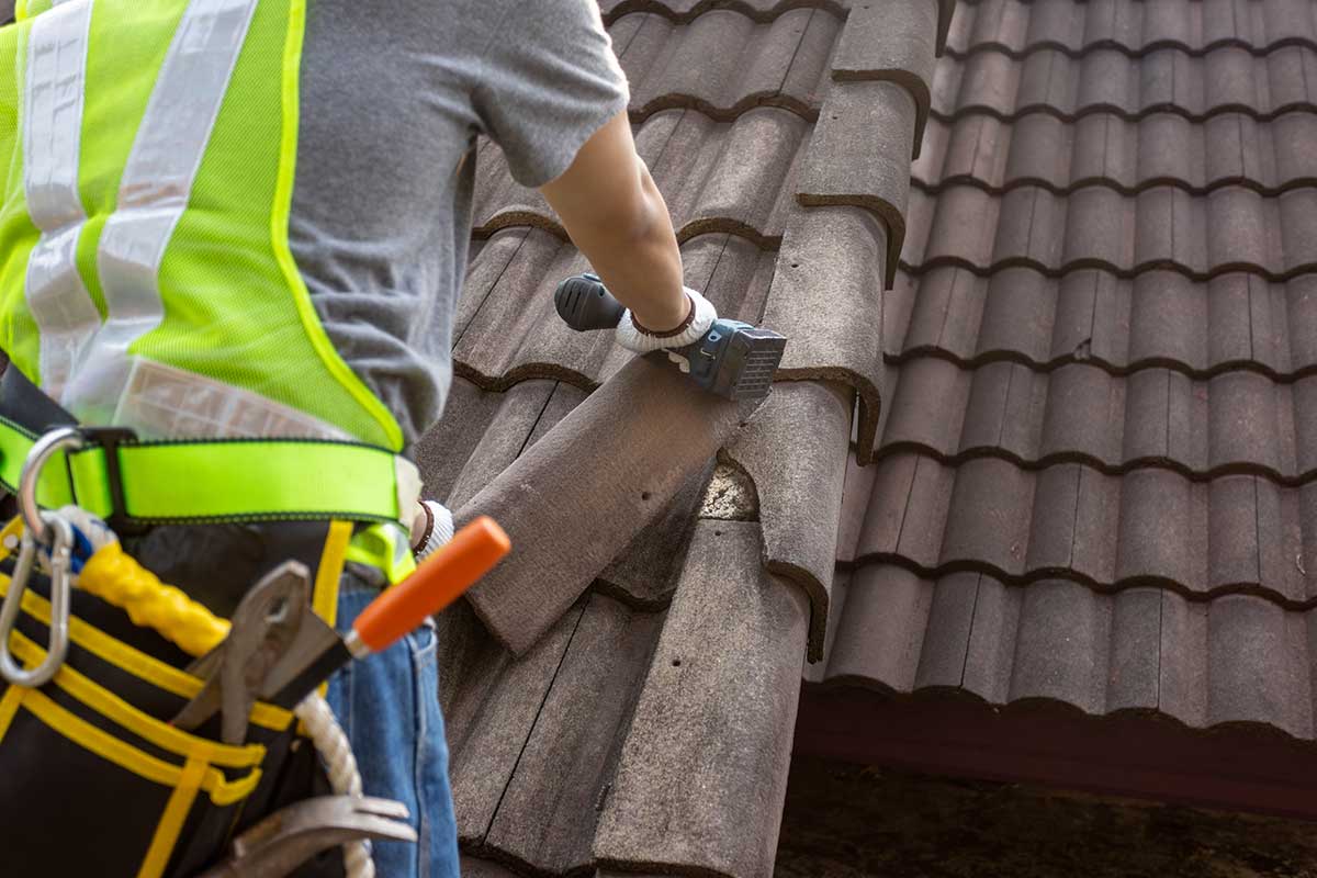 Worker man replace tile of the old roof